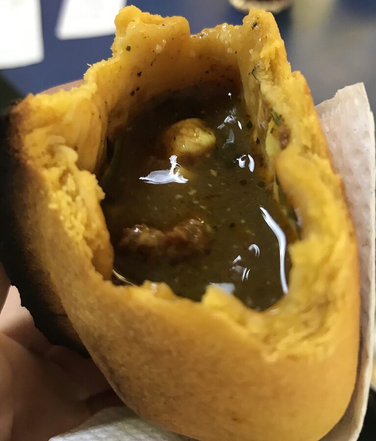 Bolivian salteña interior cross-section showing broth and filling